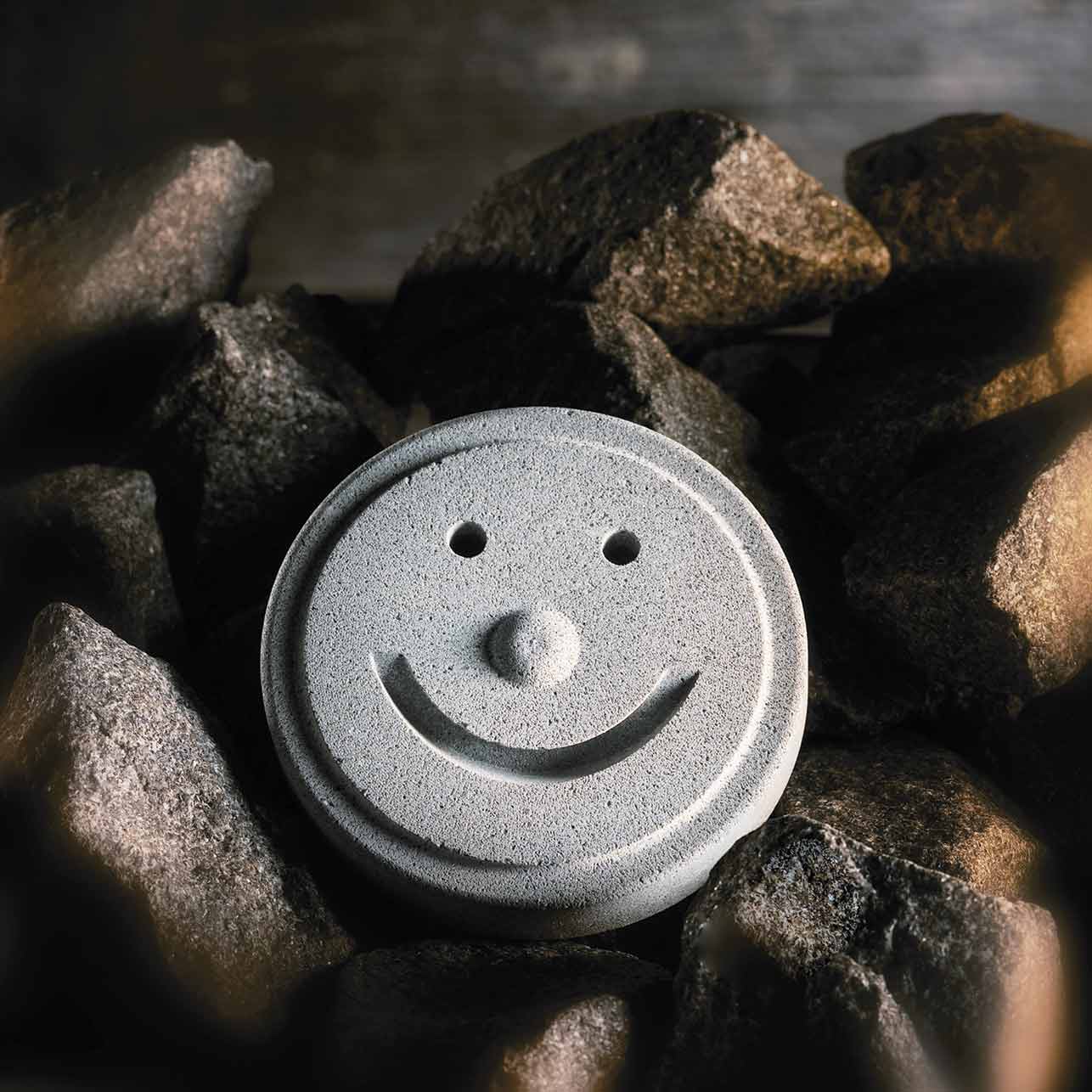 Pierre de nageur avec visage souriant entre les rochers pour sauna et bien-être.