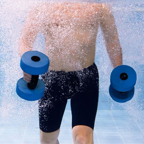 Homme avec des haltères aquatiques bleus et des dumbbells dans la piscine.