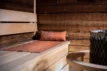 Coussin de sauna Rento Pino marron sur un banc en bois dans un sauna.