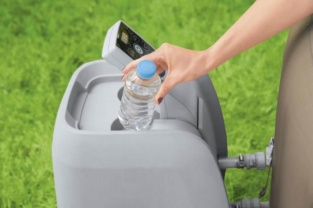 Main avec bouteille d'eau près d'un spa gonflable, détente et confort.