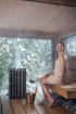 Femme dans un sauna à l'intérieur en bois avec vue sur un paysage enneigé.