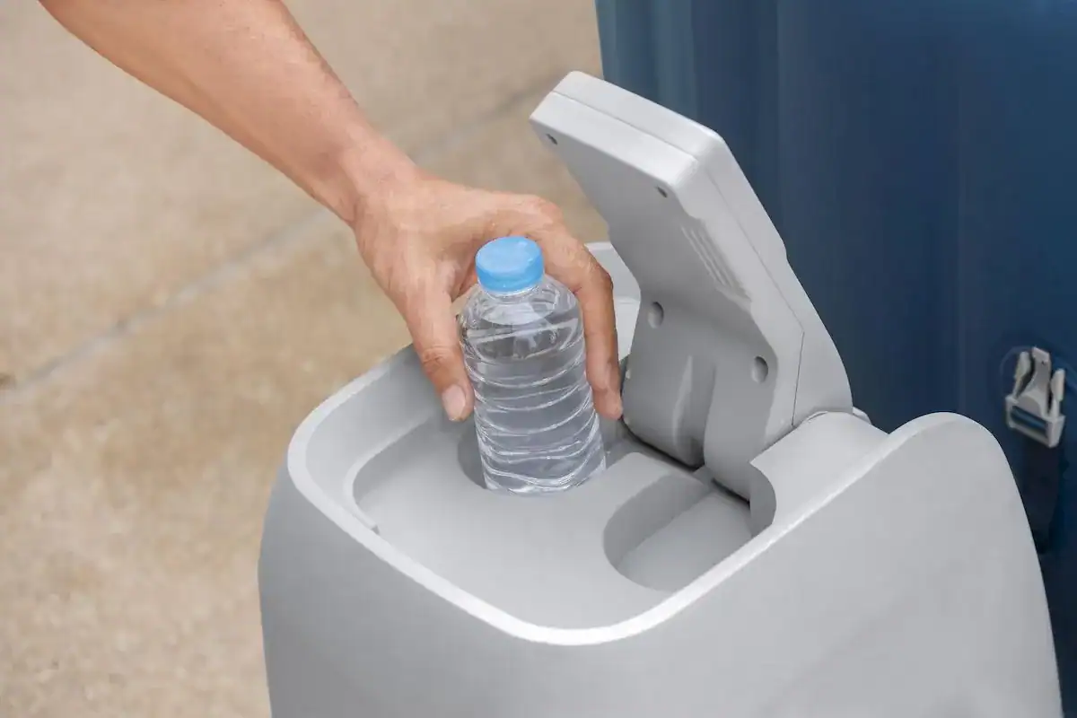 Une main place une bouteille d'eau dans le spa gonflable avec technologie AirJet.