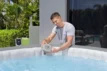 Un homme remplit une piscine Piscine.shop avec un système d'eau salée pour se détendre.