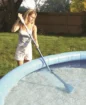 Un enfant utilise un aspirateur de piscine pour nettoyer la piscine.