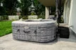 Jacuzzi extérieur de luxe sur terrasse avec jardin et mobilier de jardin.