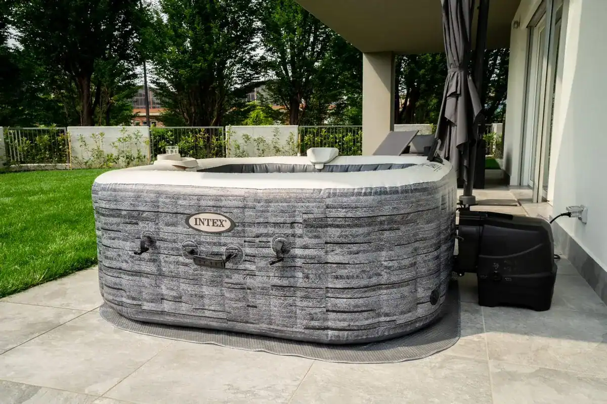 Jacuzzi extérieur de luxe sur terrasse avec jardin et mobilier de jardin.