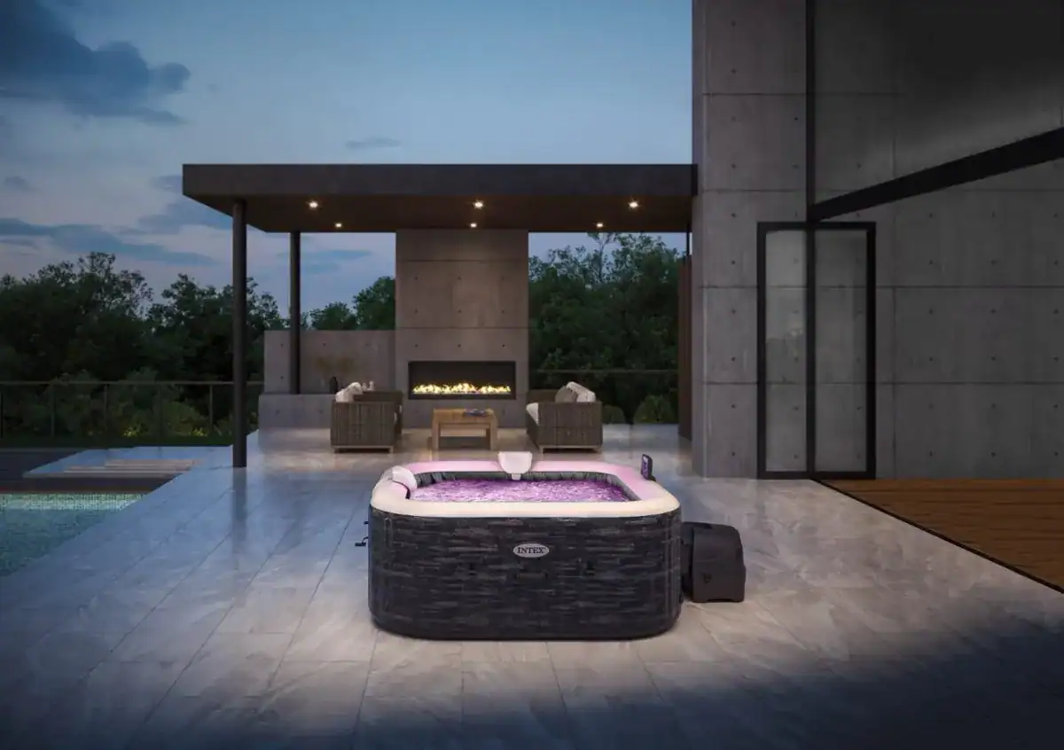Jacuzzi extérieur de luxe sur terrasse avec fauteuils lounge confortables et cheminée extérieure.