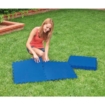Un enfant qui gonfle et déplie un tapis de piscine gonflable dans le jardin.
